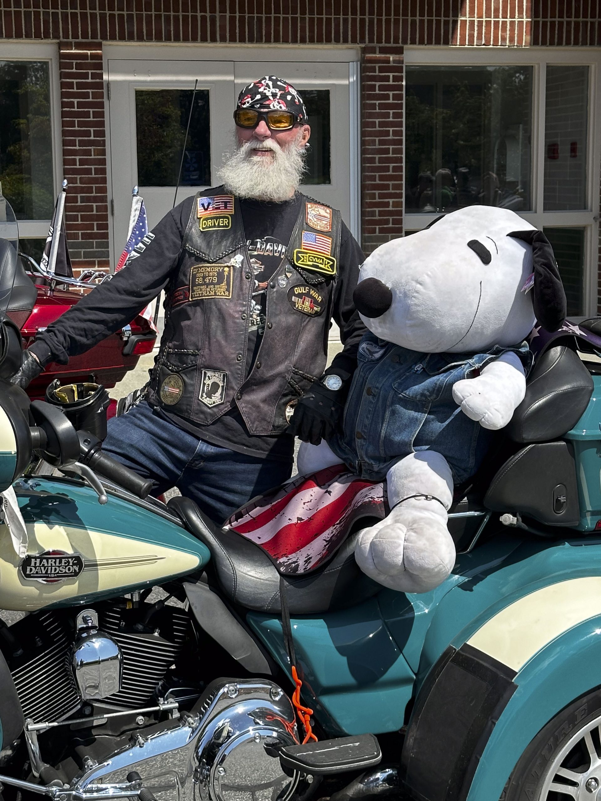 A biker shows off his passenger, a giant stuffed Snoopy